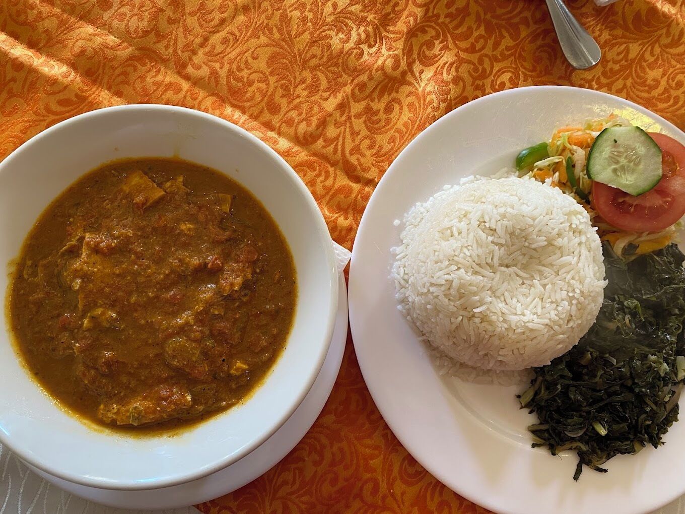 Un plato con arroz blanco, una ensalada de verduras y un tazón de curry.
