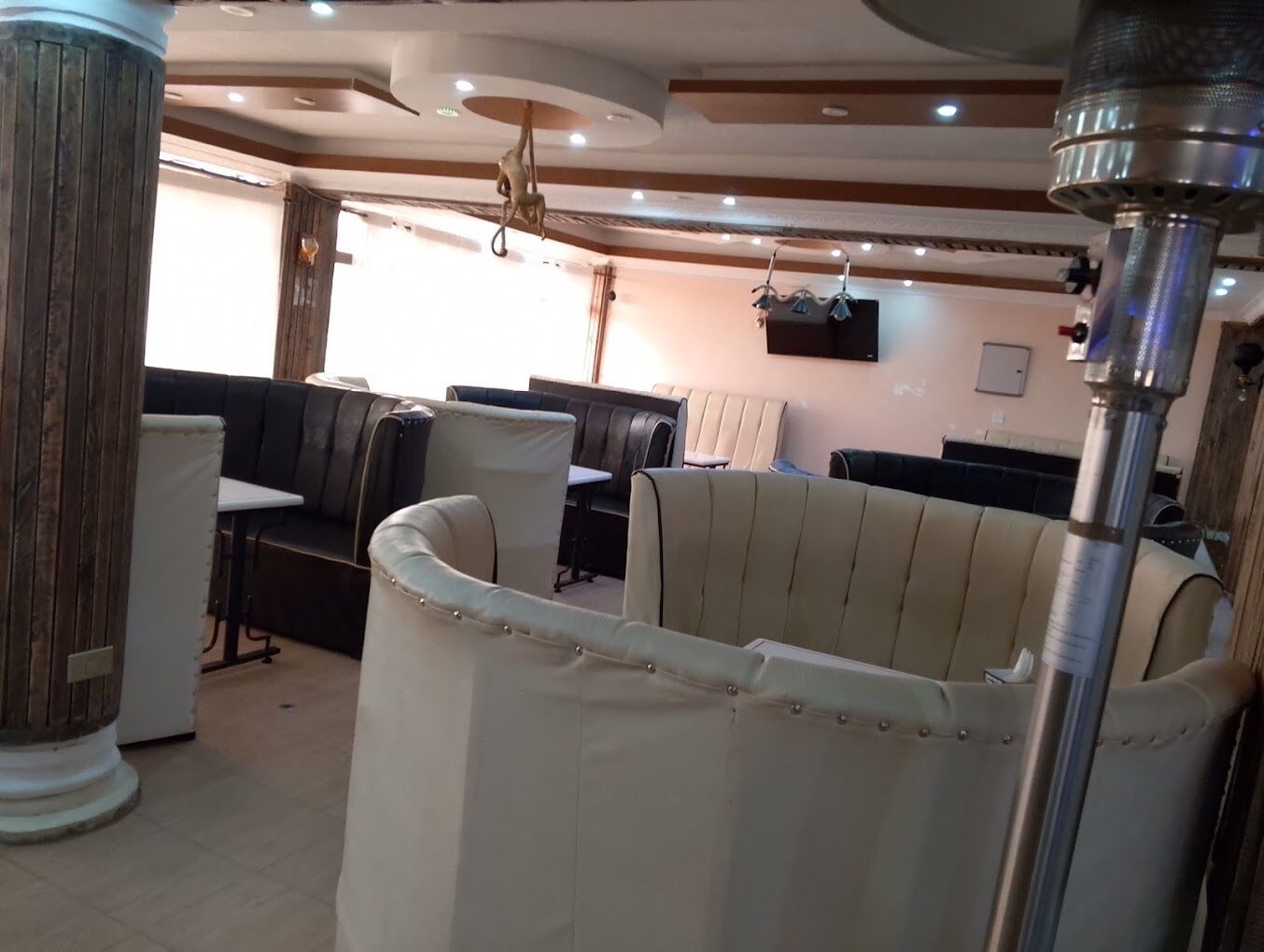 A restaurant interior with booth seating, a television mounted on the wall, and a ceiling with recessed lighting.