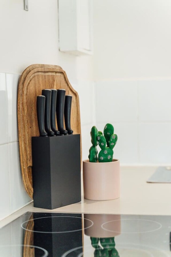A kitchen counter with a knife block, a wooden cutting board, and a cactus plant. - Beachy Keen on Moseley - Laid-Back Stay by the Jetty (Glenelg)