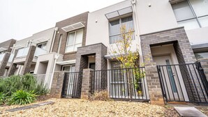 Une rangée de maisons de ville modernes, avec des éléments en brique, de grandes fenêtres et une entrée sécurisée par un portail.