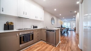 Une cuisine moderne avec des armoires blanches, des appareils en acier inoxydable et un plancher en bois.