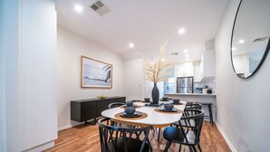 Un espace repas moderne avec une table ronde, des chaises noires et un buffet en bois foncé.