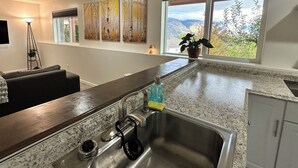 A modern kitchen with a granite countertop, stainless steel sink, and a window with a mountain view. - 40 mile view at 5,000 ft on the bench of Ben Lomond (Ogden)