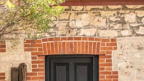 A black door with a metal handle, set in a brick wall with a stone arch above.