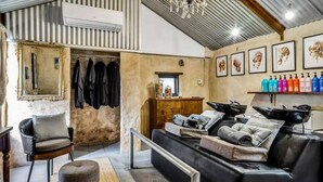 A salon with a vintage aesthetic, featuring a large mirror, a sofa, and a hair washing station.