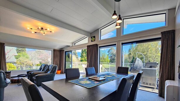 Una habitación amplia con una gran mesa, varias sillas y un sofá. Cuenta con ventanas grandes que ofrecen luz natural y vistas al exterior.