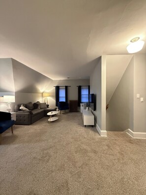 A living room with a sofa, a coffee table, a TV, and a staircase leading to another level.