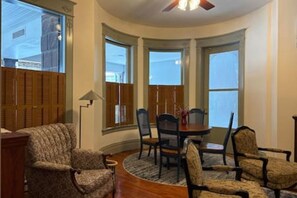 Ein Zimmer mit gewölbter Decke, HolzlĂ€den, einem Esstisch mit StĂŒhlen und einem gemusterten Sessel.