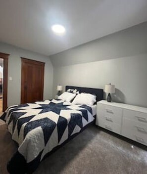 Ein Schlafzimmer mit einem Bett, Nachttischen, einer Kommode und einer TĂŒr.