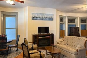 Ein Wohnzimmer mit Kamin, Fernseher, einer Couch und einem Essbereich.