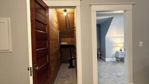 A hallway with a wooden door, a ceiling fan, and a carpeted floor. - NH3 - Historic Charm - Cozy 3BR Apartment (DuBois)