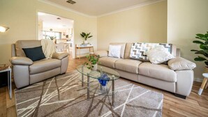 A living room with a beige sofa, a glass coffee table, and a patterned rug. - Captivating in Camden—A Well-located Family Haven (Camden Park)