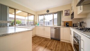 A modern kitchen with a dishwasher, stove, and large windows. - Captivating in Camden—A Well-located Family Haven (Camden Park)