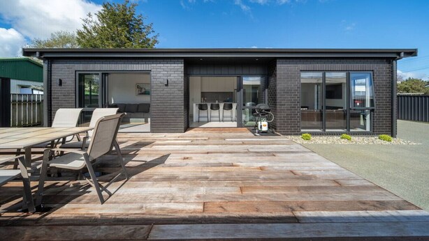 Een modern huis met een terras, een eethoek en een garage.