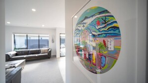 Een moderne woonkamer met een groot raam, een bank en een glazen kunstwerk aan de muur.
