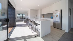 Een moderne keuken met een centraal eiland, barkrukken en een roestvrijstalen koelkast.