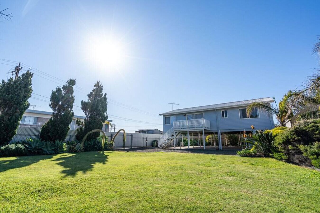 A two-story house with a balcony, surrounded by a well-maintained lawn and trees.