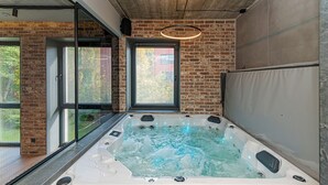 Un jacuzzi en una habitación moderna con paredes de ladrillo y ventanas amplias.