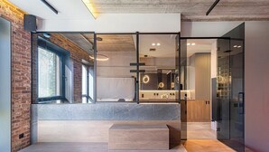 Un interior moderno con pared de ladrillo, ventanas amplias, un entresuelo y un diseño minimalista.