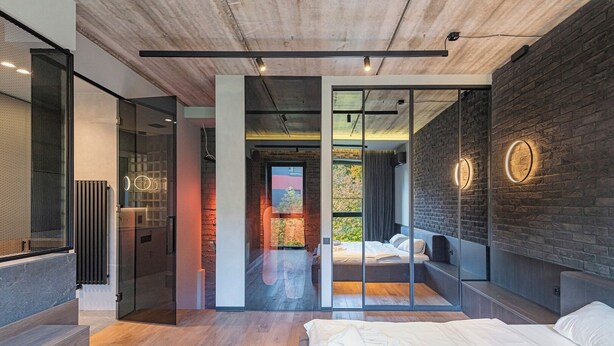 Un dormitorio moderno con una cama grande, un separador de vidrio y una pared de ladrillo.