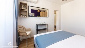 Une chambre à coucher comprenant un lit, une chaise, une petite table avec des plantes, un miroir et un luminaire suspendu.