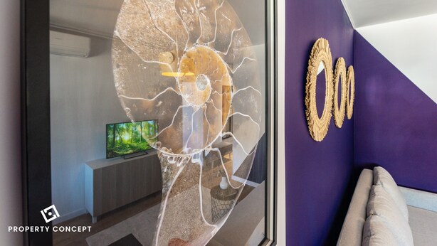 Un salon moderne agrémenté d’une grande œuvre d’art abstraite au mur, d’un téléviseur posé sur une console en bois et d’un mur d’accent de couleur violette.
