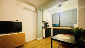 A compact living space with a TV, kitchenette, dining table, and a potted plant. - Elegant Apartment in Ivory - AC and Smart TV (Voluntari)