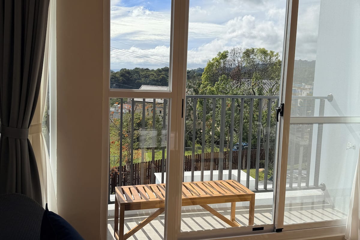 A room with a large sliding glass door leading to an outdoor balcony with a wooden table and chairs.