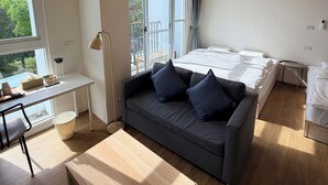 A modern room with a wooden ceiling, a large bed, a sofa, a desk, and a window with a view of greenery. - KUMOYOKU B&B (Taichung)