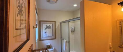Un baño con cabina de ducha de vidrio, lavabo de mármol y cuadros en la pared.