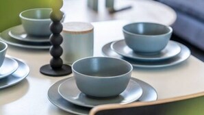 Una mesa de comedor dispuesta con fuentes y platos, un candelabro y una ventana al fondo.