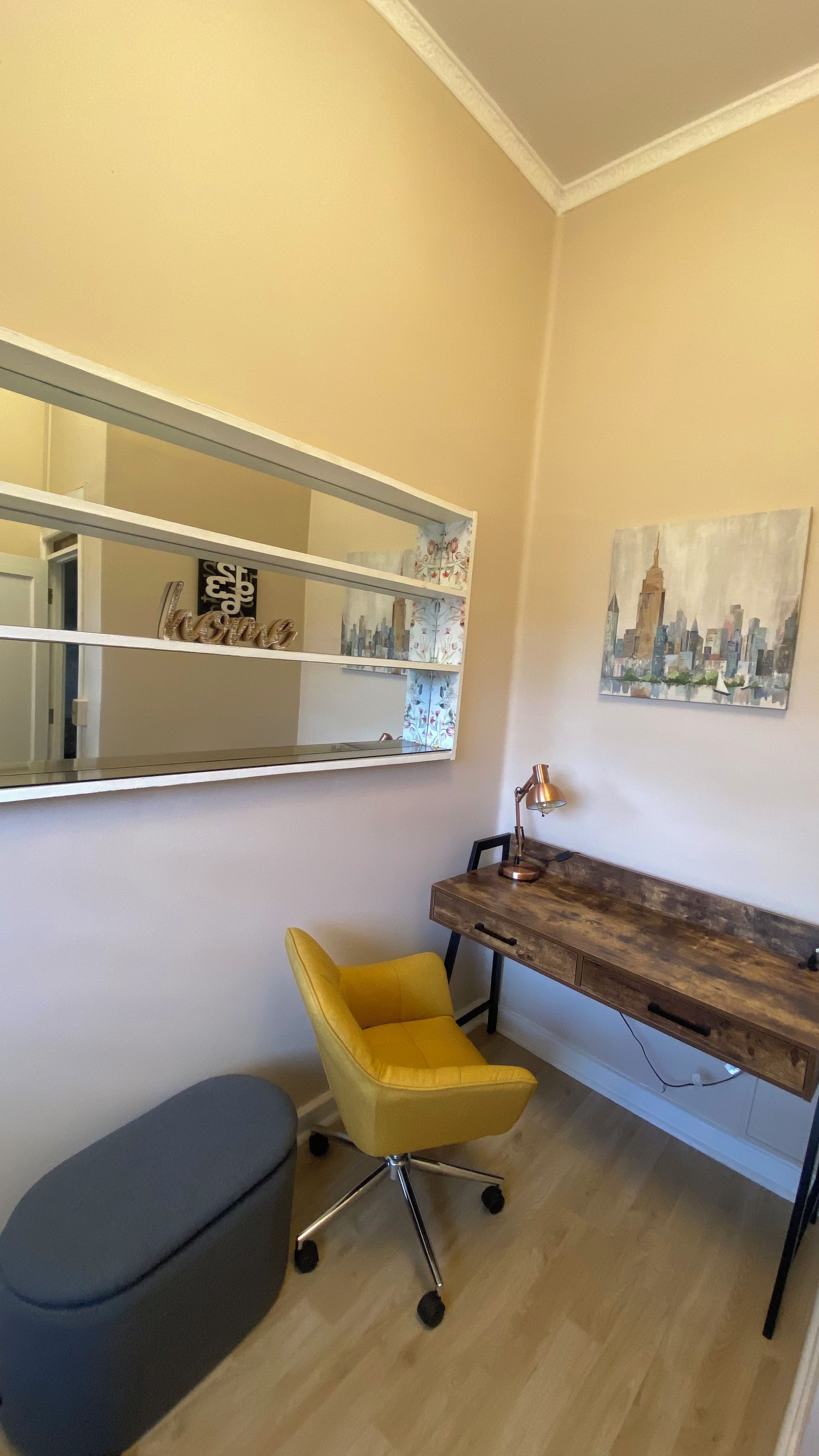 Una habitación con escritorio, silla y un espejo grande.