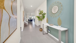 A modern hallway with a white console table, a potted plant, and a decorative mirror.