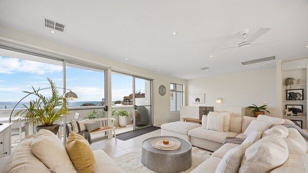 A spacious living room with a large sliding glass door leading to a balcony, a ceiling fan, and a fireplace.
