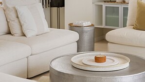 A modern living room with a white sofa, a round coffee table, and a large mirror.