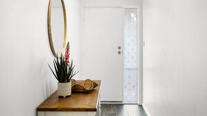 A hallway with a wooden bench, a potted plant, and a large mirror.