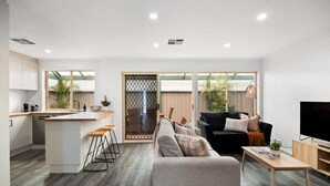 A modern living space with a kitchen, a sofa, a TV, and a dining area.