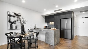 A modern kitchen with a central island, dark cabinetry, and a stainless steel refrigerator.