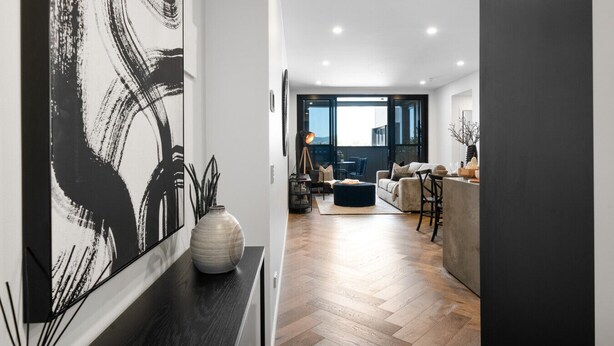 A modern living room with a large abstract painting, a vase, and a dining area with a bar.
