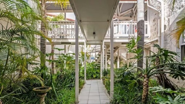 A covered walkway flanked by lush tropical plants, leading to a building with balconies. - Sea Breeze @ Smugglers Inn (Victor Harbor)