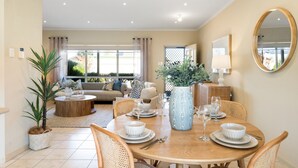 A dining area with a round wooden table set for four, surrounded by wicker chairs.
