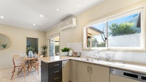 A modern kitchen with a dining area, featuring a large window, built-in appliances, and a clean, neutral color scheme.