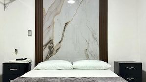 Een moderne slaapkamer met een groot bed, twee nachtkastjes en een marmeren wand.