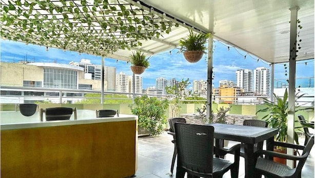 Een terras met een balie, stoelen en hangende planten.