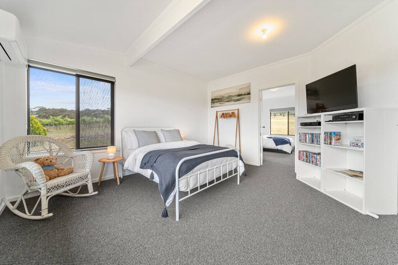 A bedroom with a bed, a rocking chair, a bookshelf, and a television.
