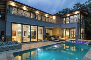 A modern house with a swimming pool, large glass doors, and outdoor seating. - Walk to Beach Private Villa in Gated Community (Tamarindo)