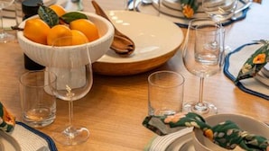 Une table à manger dressée avec des assiettes, des bols, des verres et des couverts.