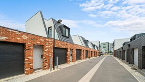 Una hilera de edificios modernos con fachadas de ladrillo y grandes puertas de garaje, presumiblemente una zona comercial o industrial.