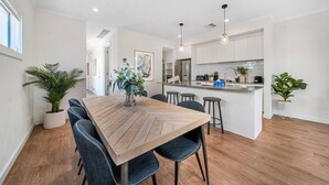 A modern kitchen with white cabinets, a wooden island, and bar stools. - Urban Luxe—A Contemporary City-Edge Haven (Mile End)