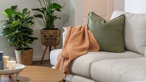 A living room with a sofa, a coffee table, and two potted plants. - Sage By The Sea—Stylish Beachside Living with BBQ (West Beach)